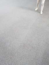 A pair of modern men's shoes placed beside folded pants on a wooden surface.
