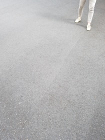 A pair of modern men's shoes placed beside folded pants on a wooden surface.