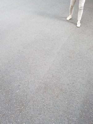 Grey sweatpants laid out on a concrete floor with soft natural light highlighting the fabric texture.