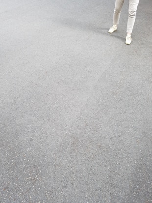 A pair of light-colored shoes and pants on a gray, textured surface.