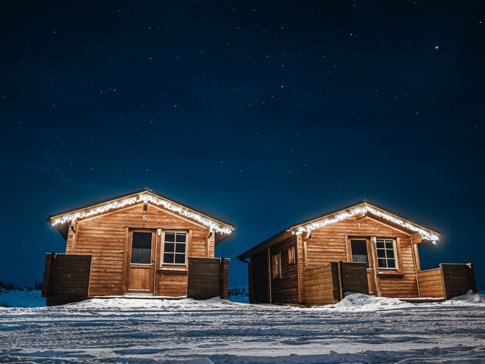 casa di legno marrone su terreno innevato durante la notte