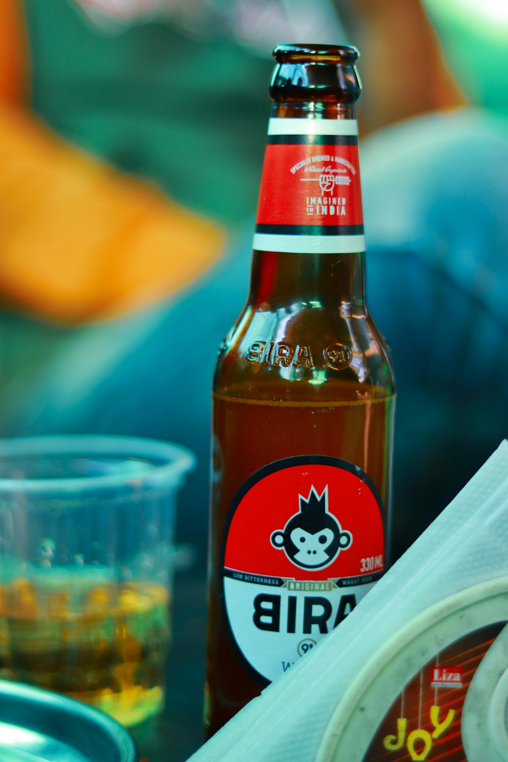 red and white labeled bottle beside clear drinking glass