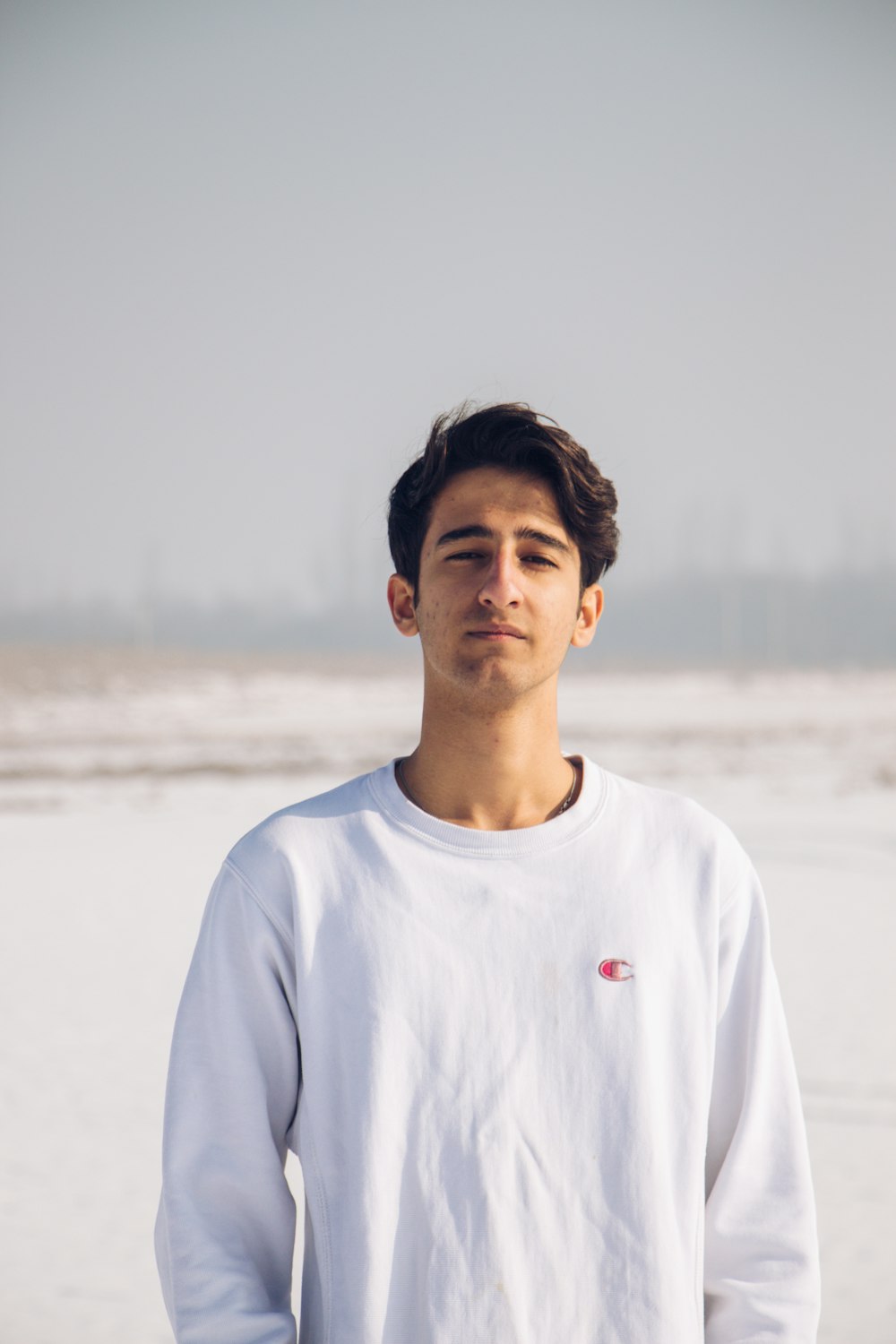 man in white crew neck shirt standing on beach during daytime