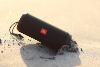 black jbl portable speaker on white and black textile
