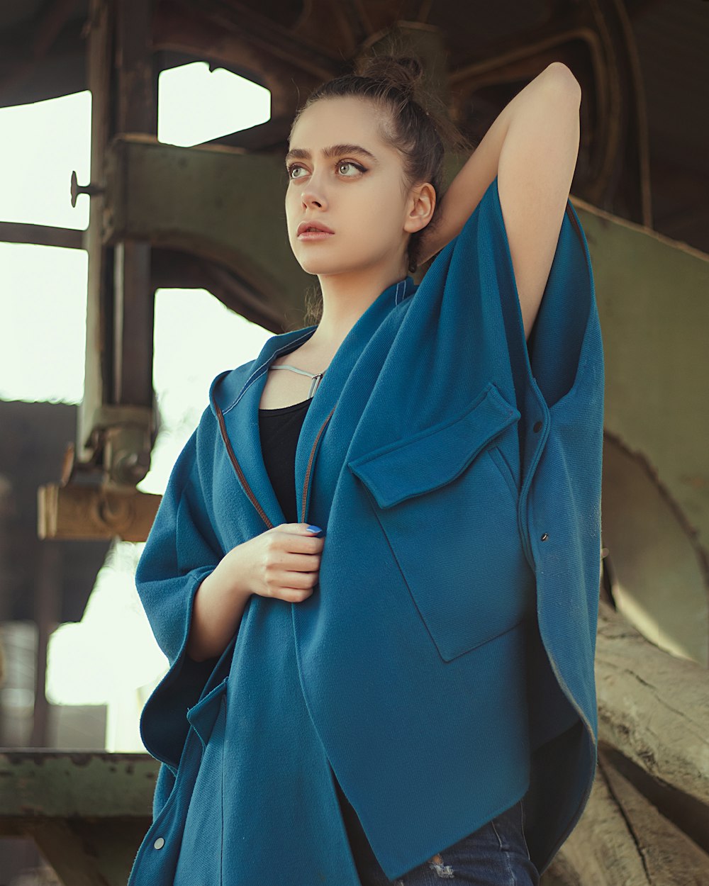 woman in blue blazer standing near brown wooden post during daytime