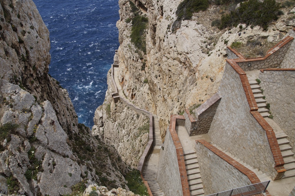 brown concrete stairs on cliff near body of water during daytime