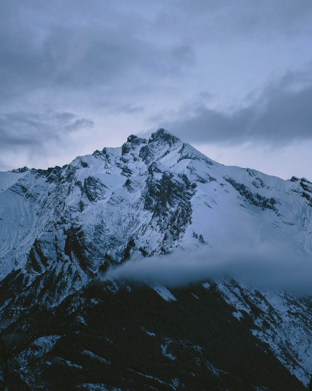 montanha coberta de neve sob céu nublado durante o dia