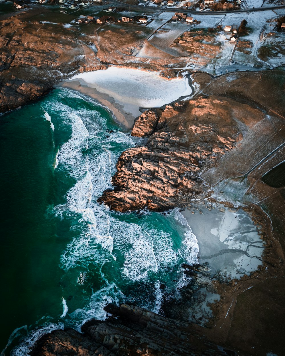 aerial view of brown and gray mountains beside body of water during daytime