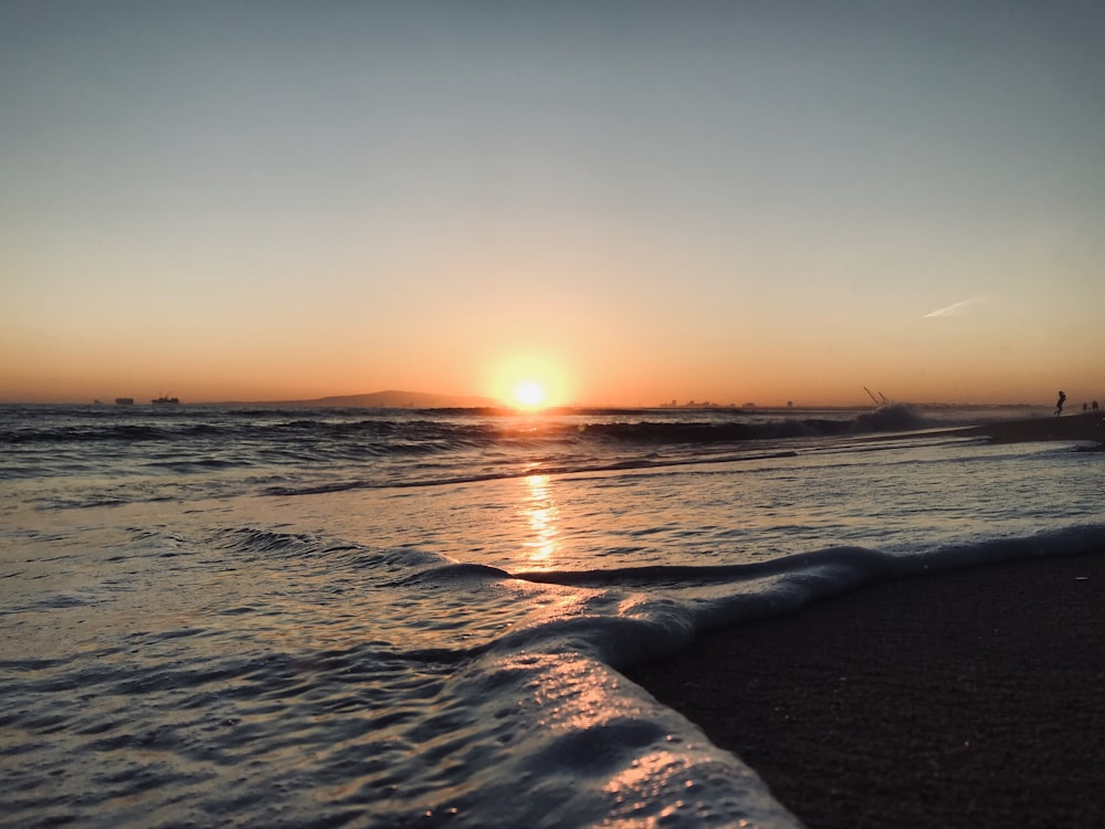 sea waves crashing on shore during sunset