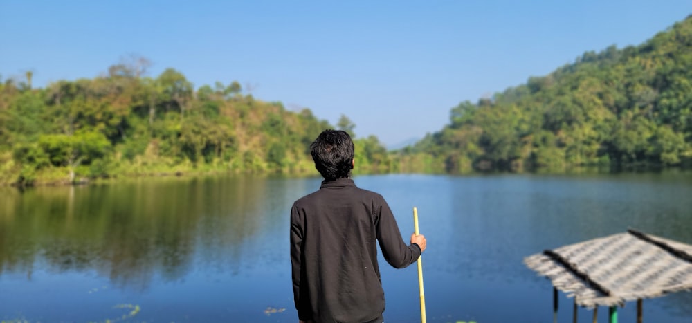 man in gray hoodie holding yellow stick near lake during daytime