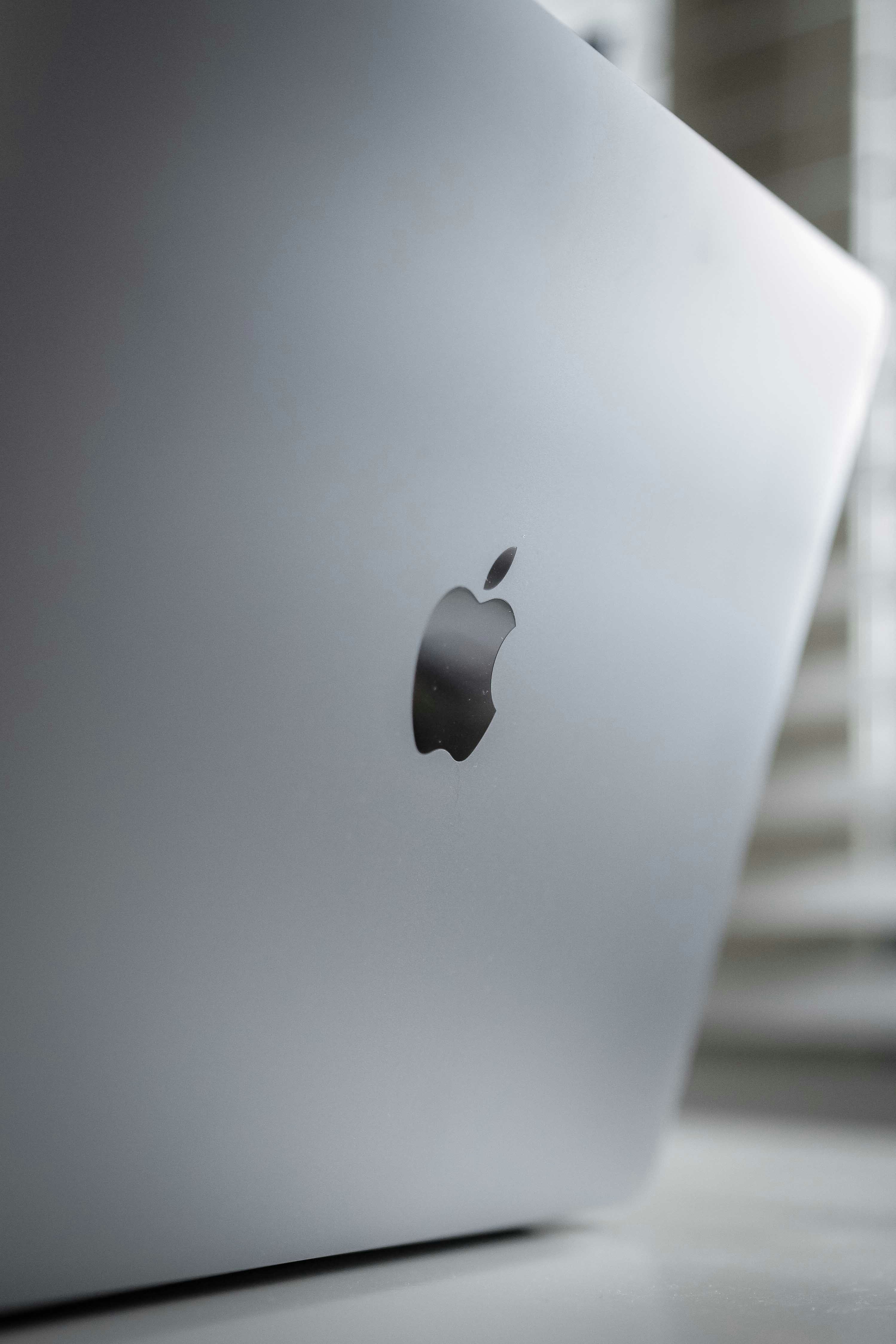 Silver MacBook laptop open on white desk, clean bright studio environment