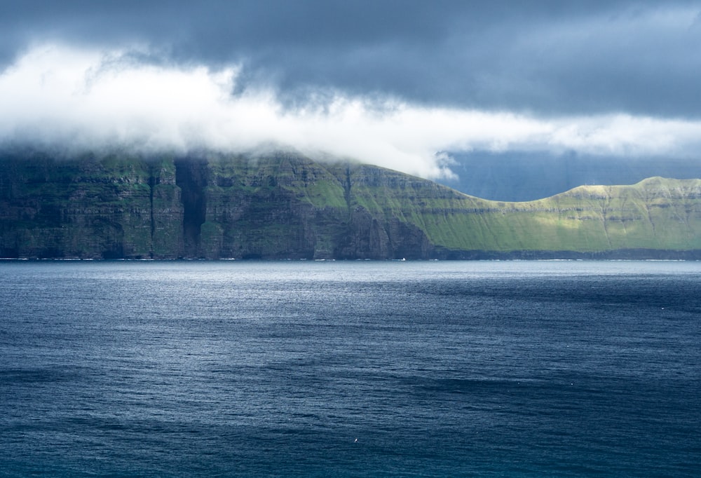 green mountain beside body of water