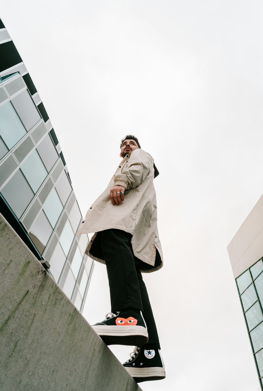 man in gray hoodie and black pants sitting on gray concrete wall