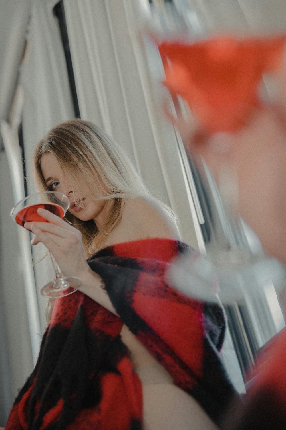 Mujer en vestido rojo y negro con hombros descubiertos sosteniendo una taza de cerámica blanca