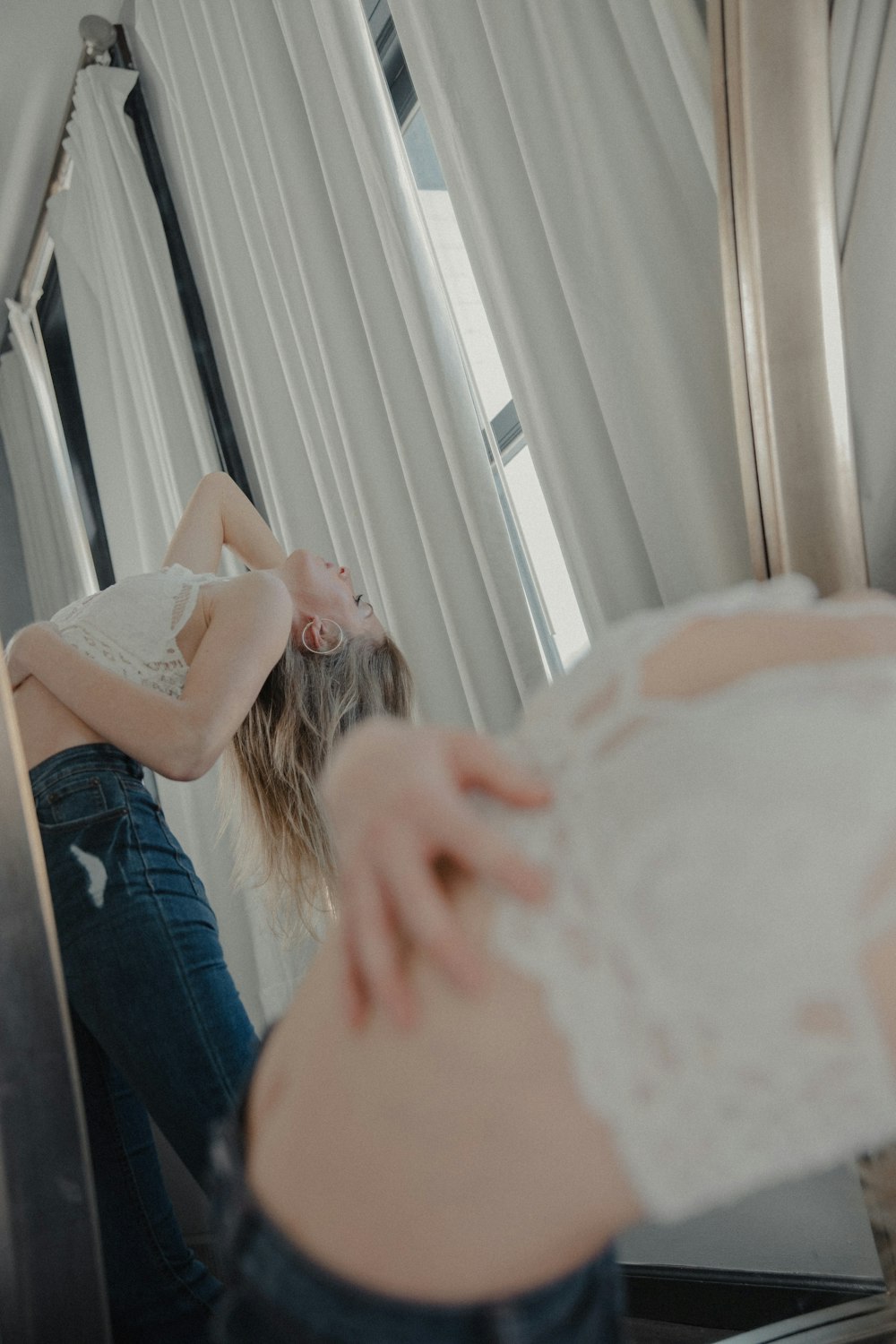 Frau in blauen Jeans sitzt auf dem Bett