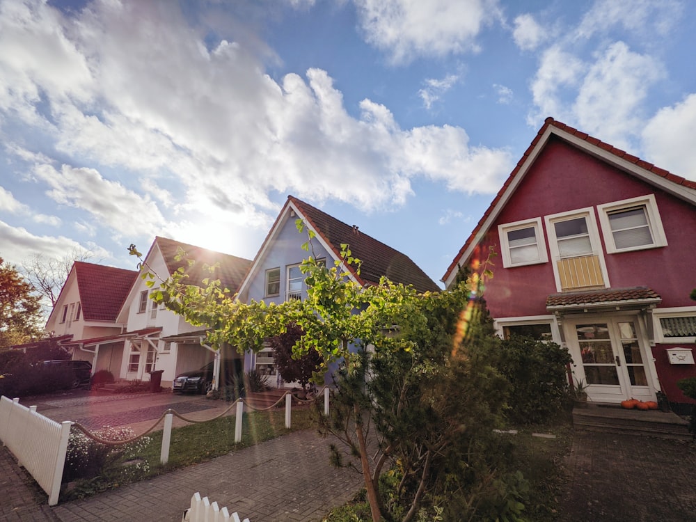 Grüne Bäume in der Nähe des roten und weißen Hauses tagsüber unter blauem Himmel