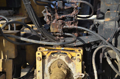 Close-up of a hydraulic pump being serviced by a technician in an industrial workshop.