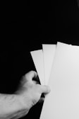 Hands arranging monochrome printed materials on a white table.