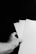 A hand holding three white sheets of paper against a dark background. The paper sheets are fanned out, and the scene is captured in black and white.