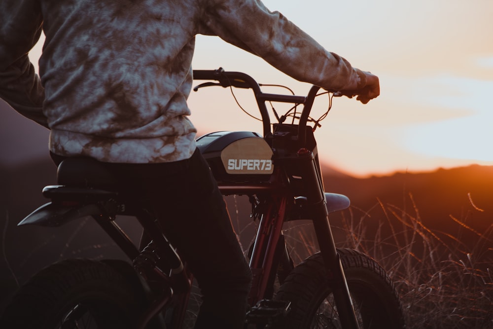 person in gray jacket riding black motorcycle during sunset