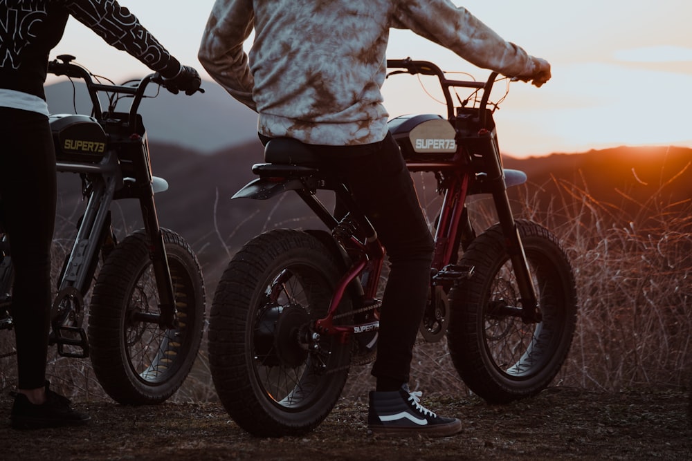 person in white and black jacket riding black and red mountain bike during sunset