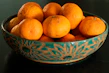 Close-up of a cozy ceramic bowl with a warm orange glaze, resting on a linen cloth beside fresh fruit.