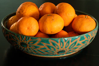 A vibrant ceramic bowl with hand-painted patterns, filled with fresh fruit on a rustic kitchen counter.