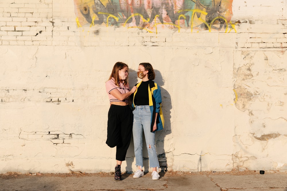 woman in black tank top and blue denim jeans standing beside woman in blue denim jeans