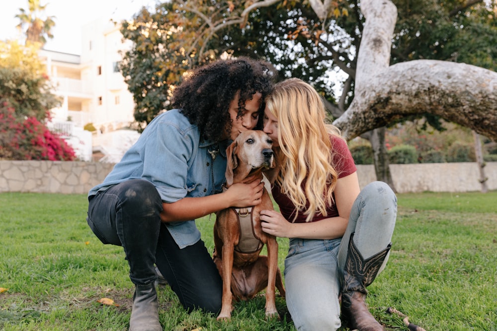 Mujer con camiseta gris sosteniendo un perro de pelo corto marrón