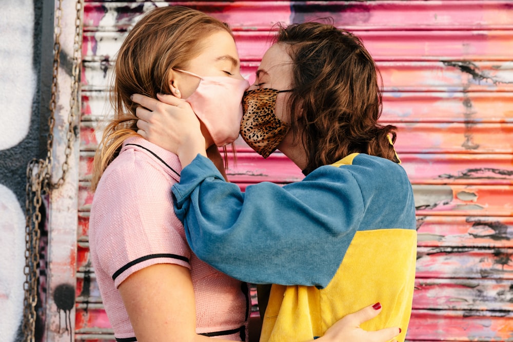 Ragazza in felpa con cappuccio blu e gialla che bacia la donna in camicia bianca