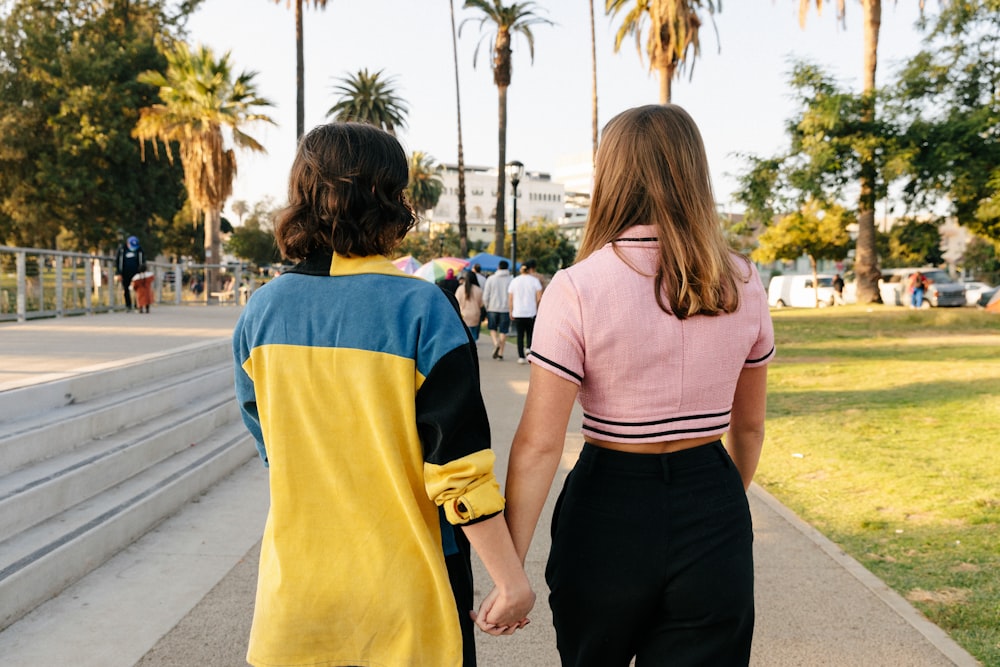 woman in pink shirt and black pants standing on sidewalk during daytime