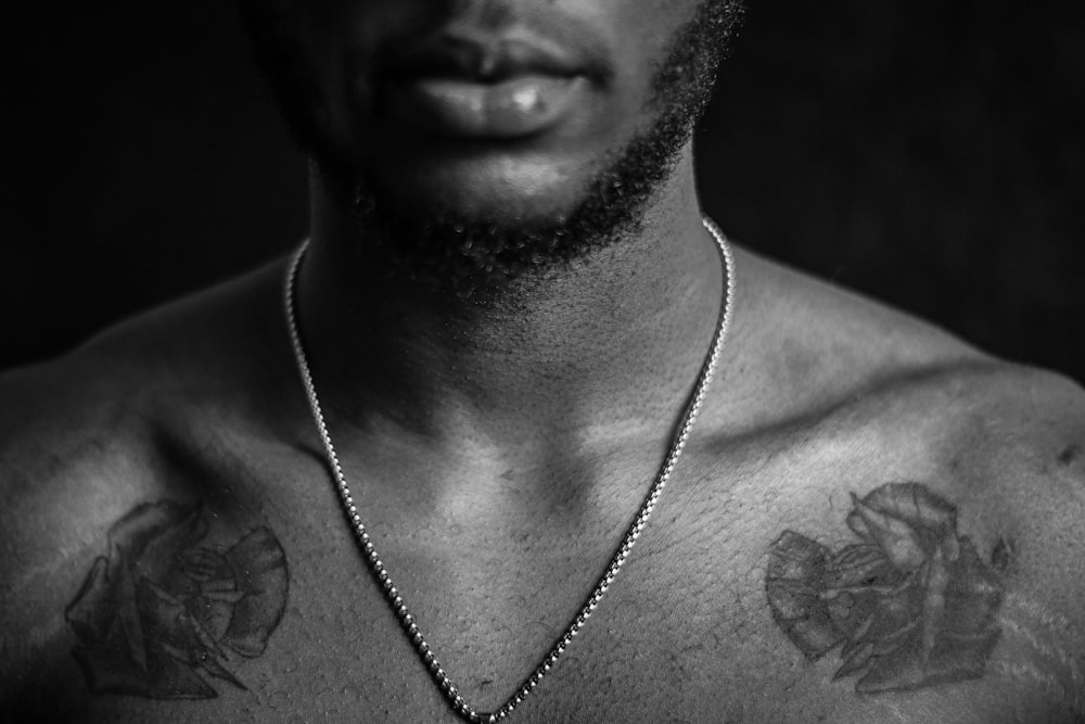 grayscale photo of man wearing silver necklace