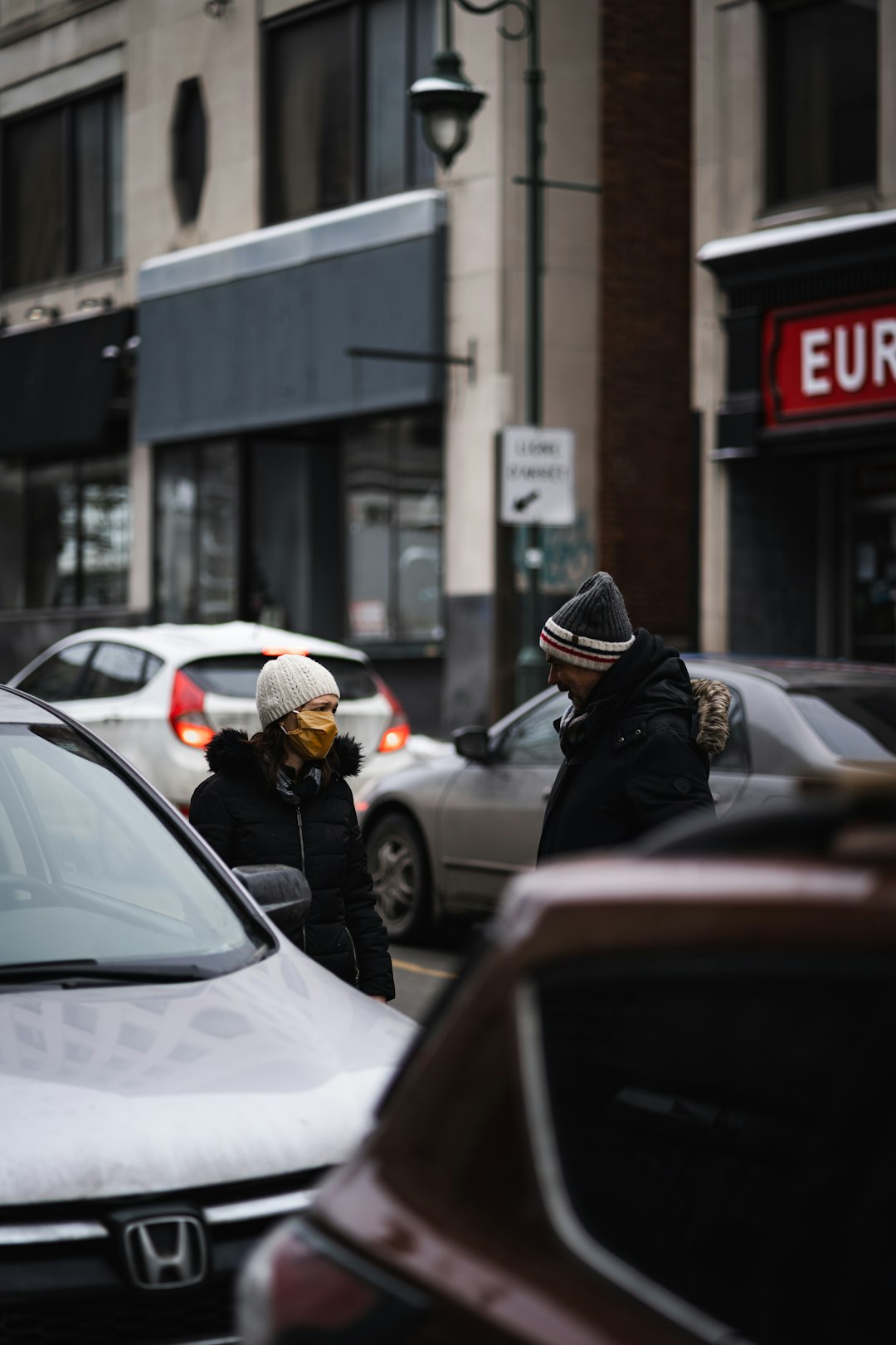 man in black jacket and black helmet standing beside black car during daytime