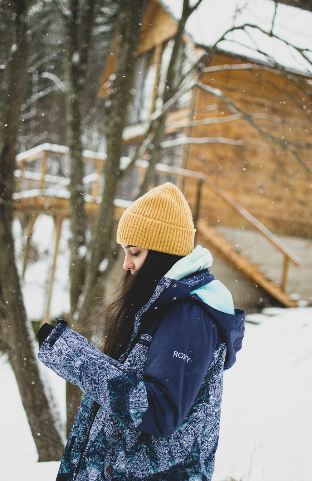 woman in yellow knit cap and black jacket standing on snow covered ground during daytime