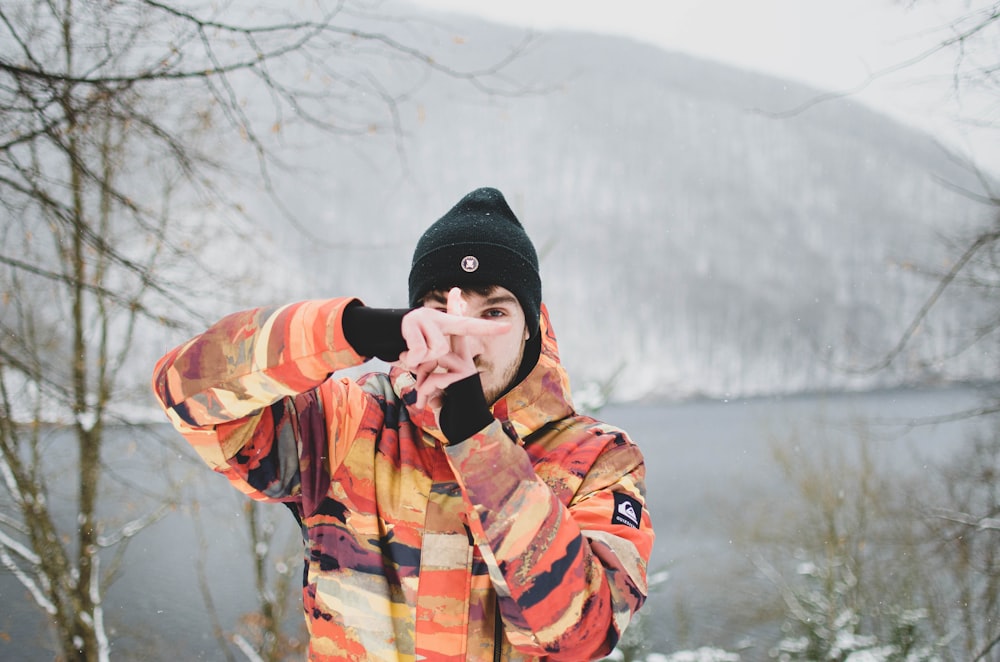 man in black knit cap and plaid coat standing near snow covered ground during daytime