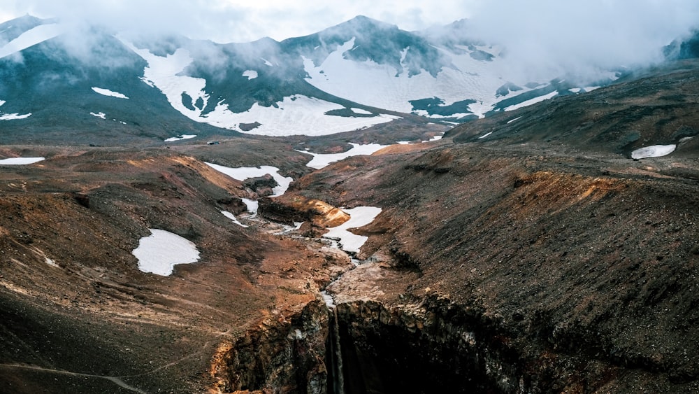 Montagnes brunes et grises sous des nuages blancs pendant la journée