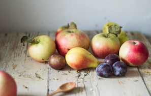 Fresh ripe apples and pears arranged on a rustic wooden table.