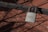 A rusted padlock branded 'Sargent' hangs on a wire fence, casting shadows over the geometric pattern of the metal grid.