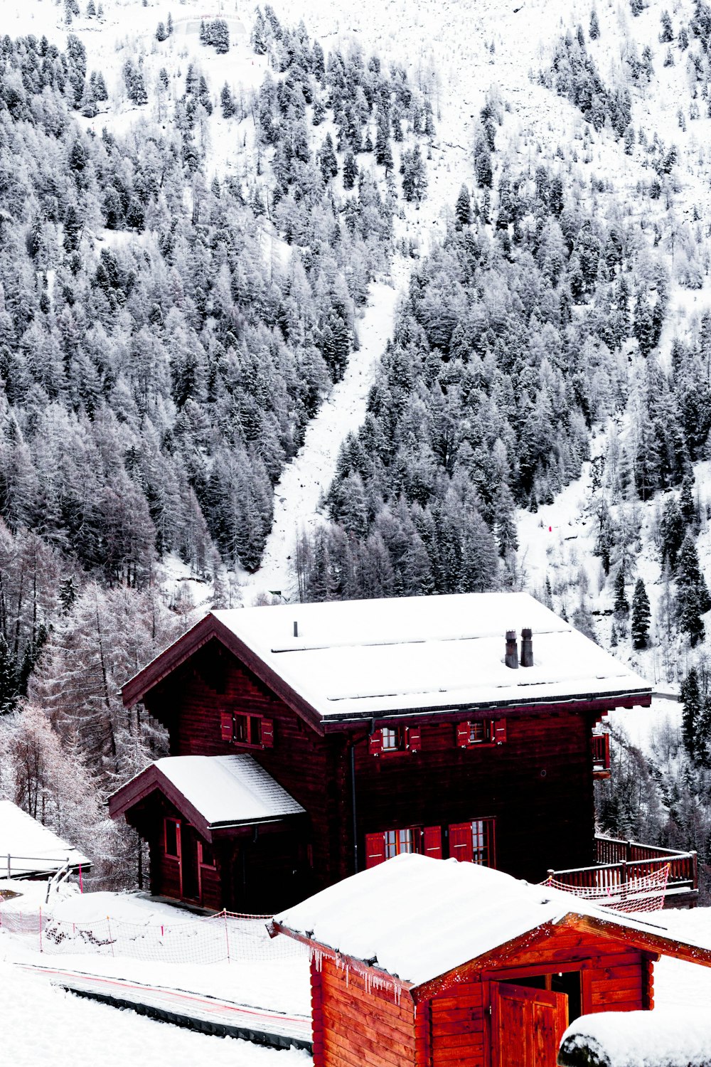 red wooden house near snow covered mountain