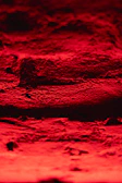 Close-up of the textured surface of a freshly fired red clay brick glowing with #d49e58 highlights.