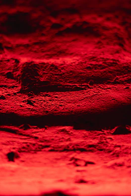 Close-up of the textured surface of a freshly fired red clay brick glowing with #d49e58 highlights.