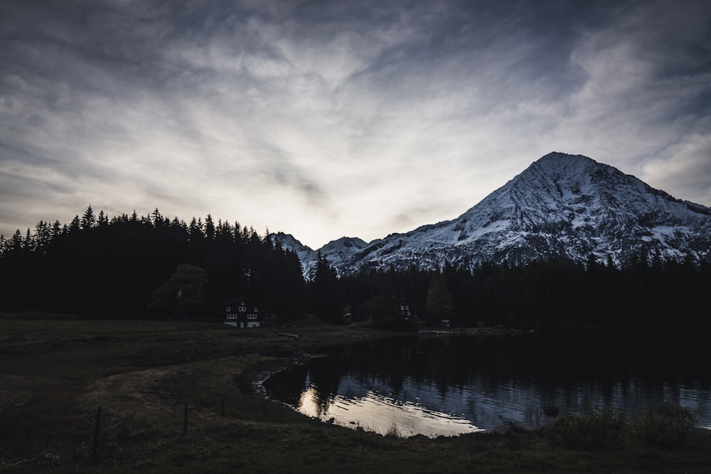 lake near trees and mountain under cloudy sky