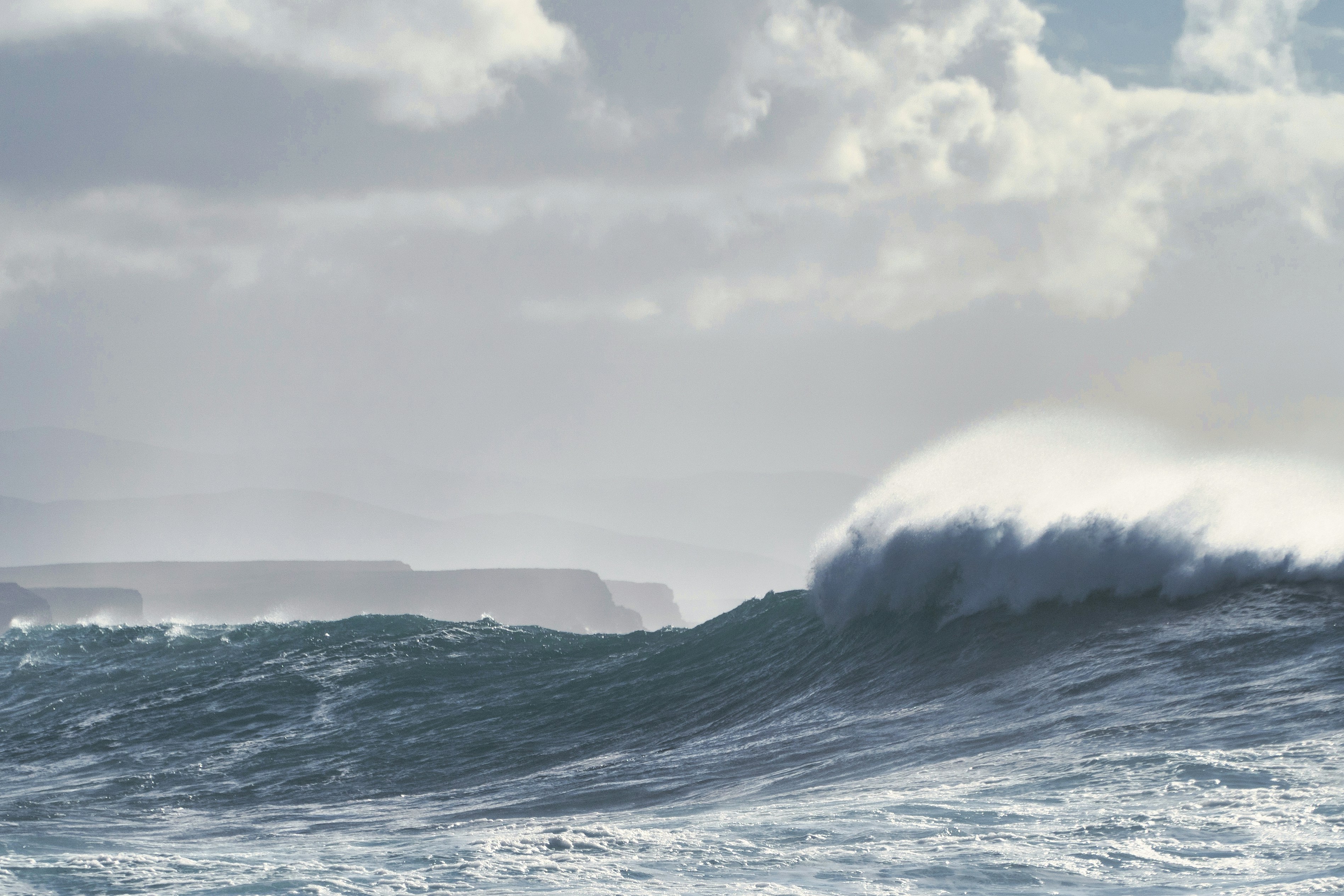 ocean waves under white clouds during daytime