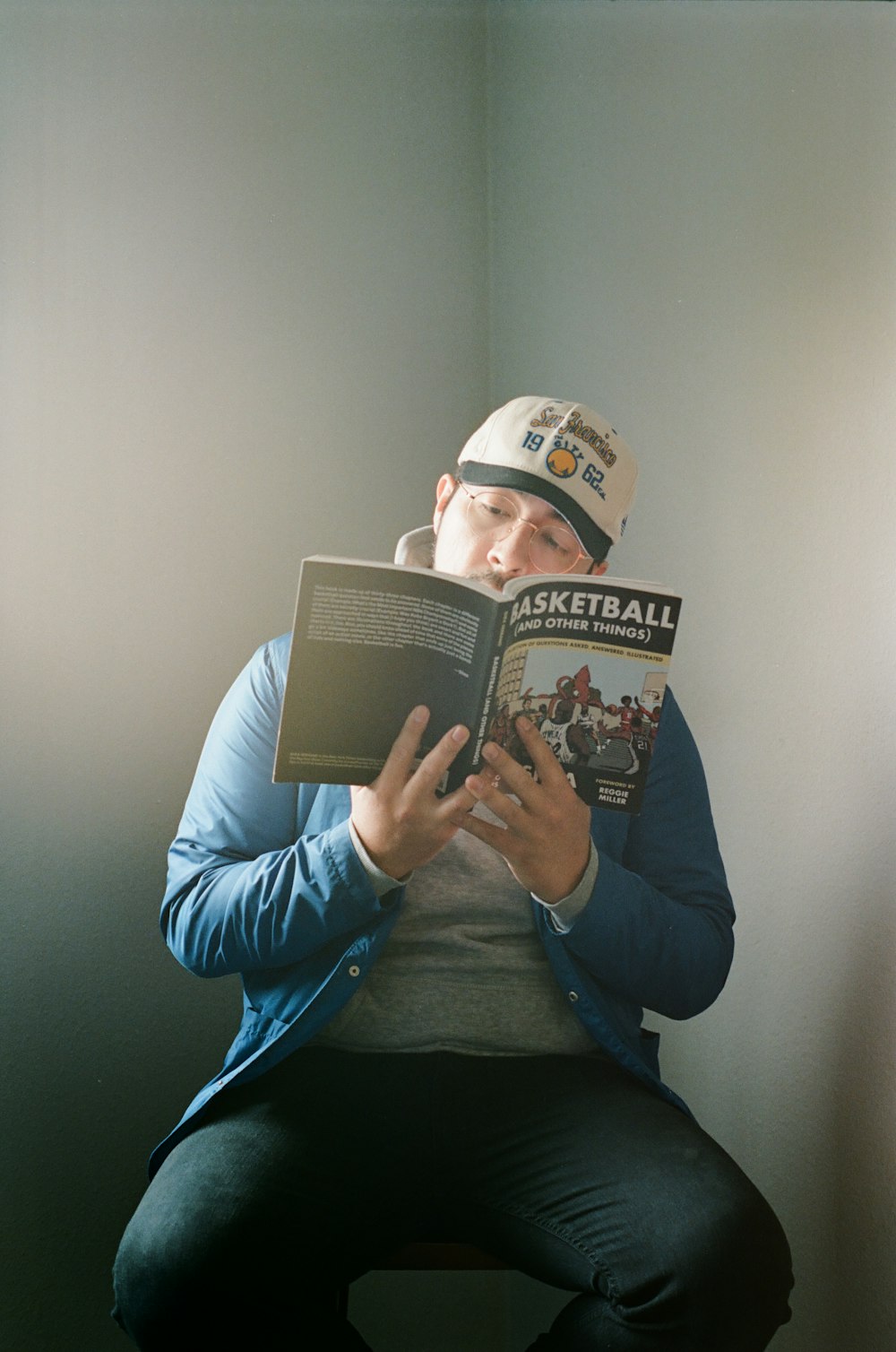 man in blue jacket reading book