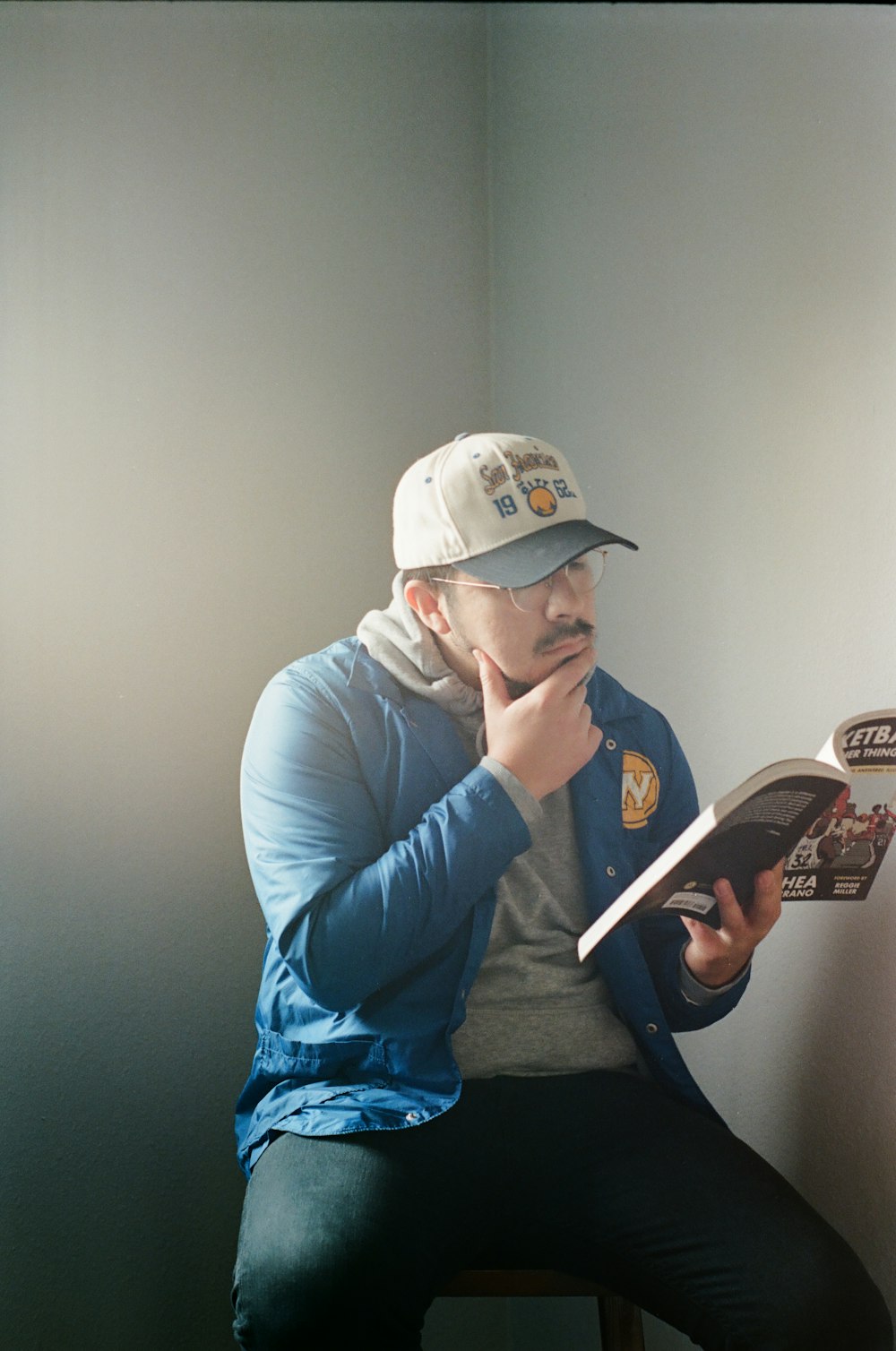 man in gray hoodie and blue pants sitting on gray couch