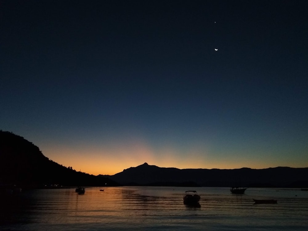 silhouette of mountain near body of water during night time