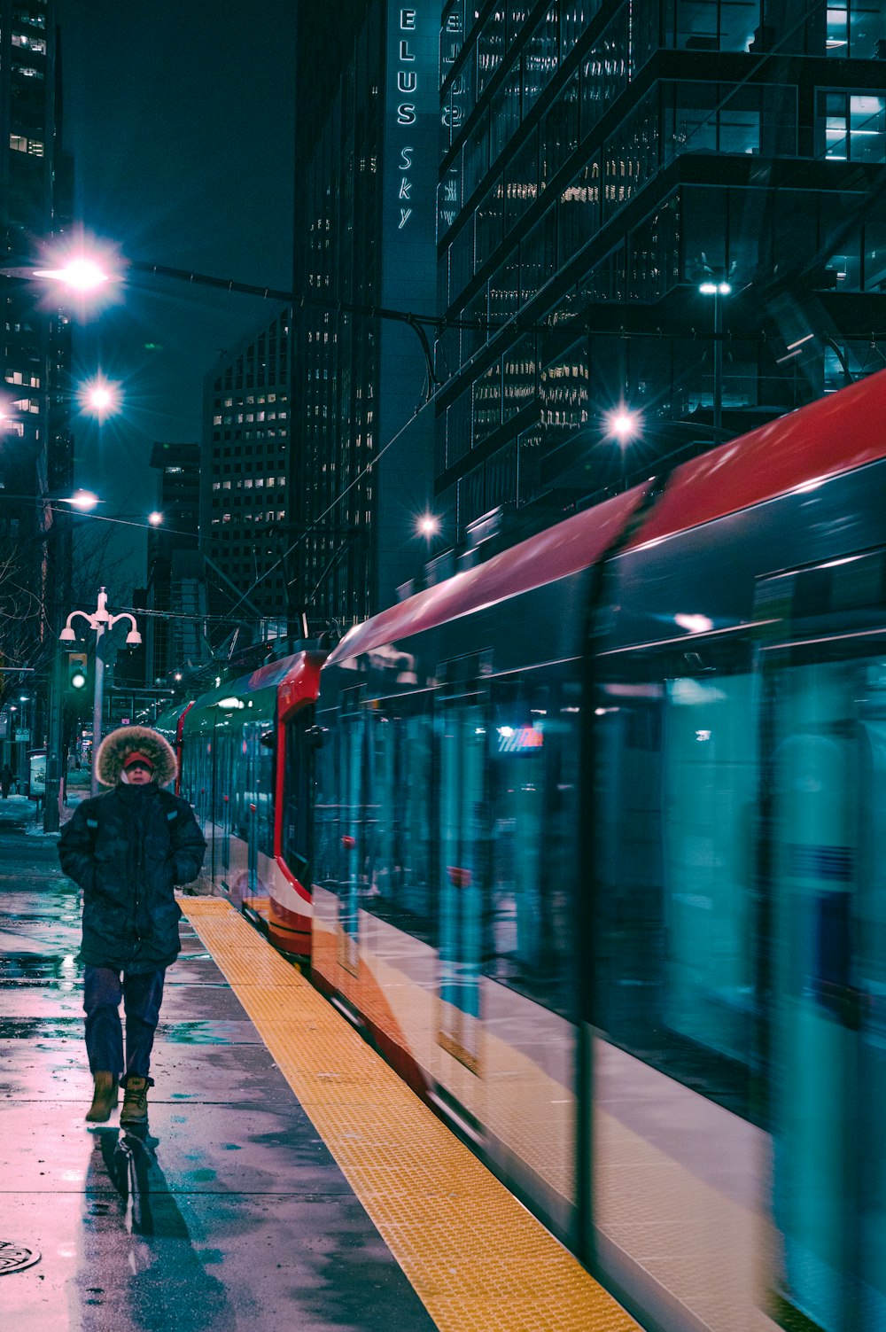 Mann in schwarzer Jacke steht nachts am Bahnhof
