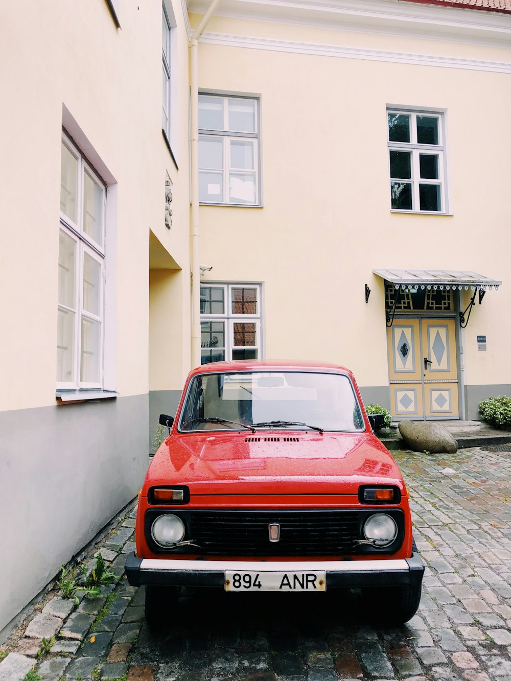 red car parked in front of white concrete building