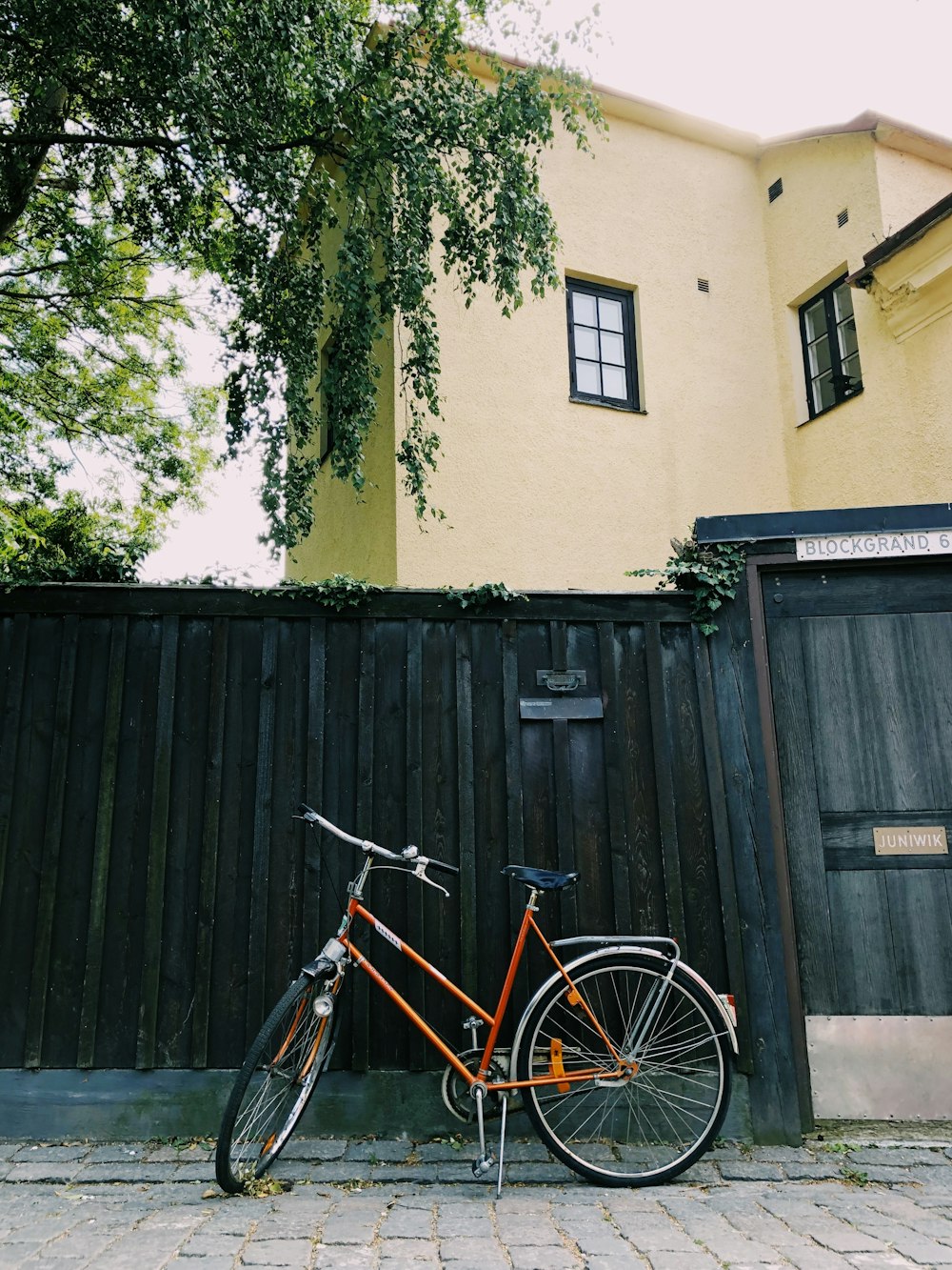 yellow city bike parked beside brown wooden fence
