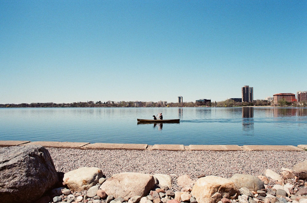 person in black shirt standing on brown rock near body of water during daytime